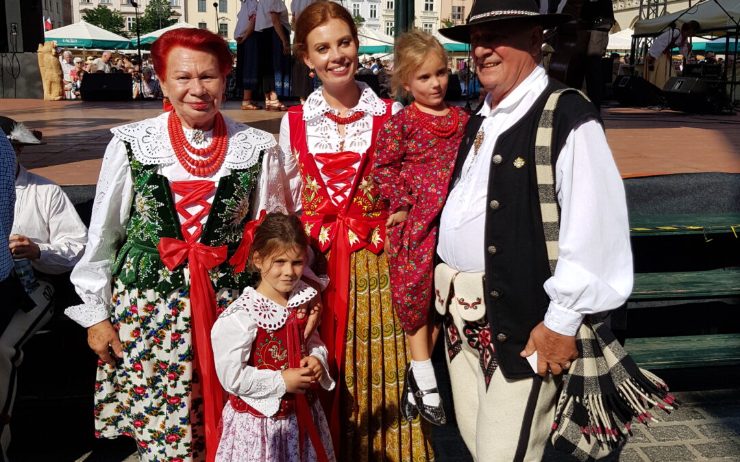 A group of performers in traditional Polish folk costumes during a lively folklore show in Kraków.